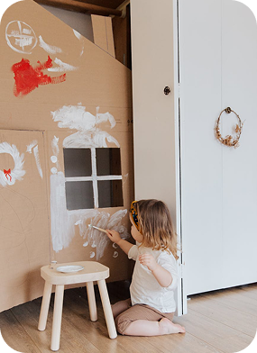Child painting cardboard house